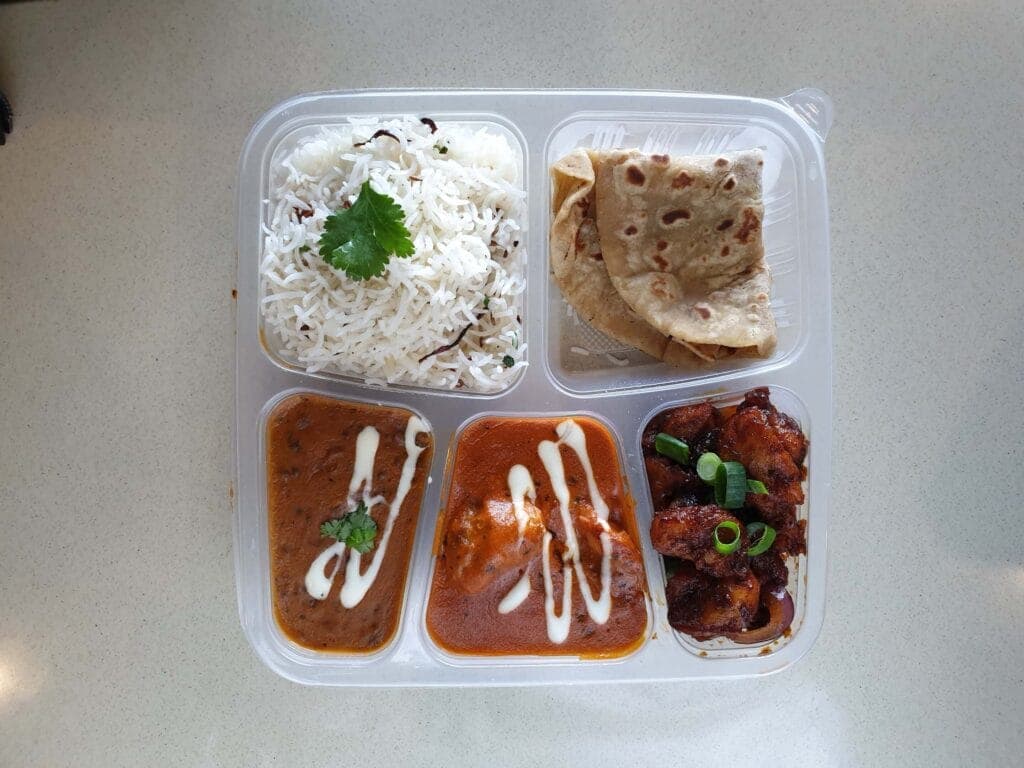 A packed Dosa Hut catering tray of rice, roti, dal makhani, butter chicken and chilli chicken