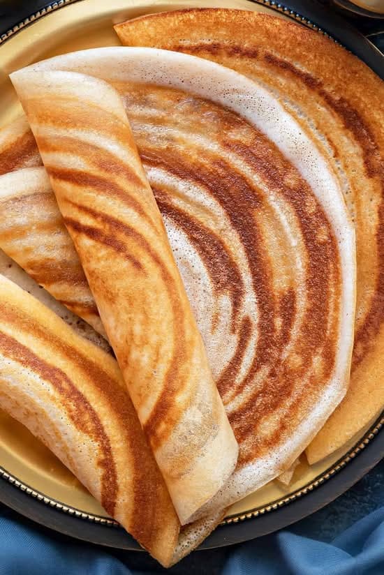 Extra-thin paper dosa rolled tall on the plate